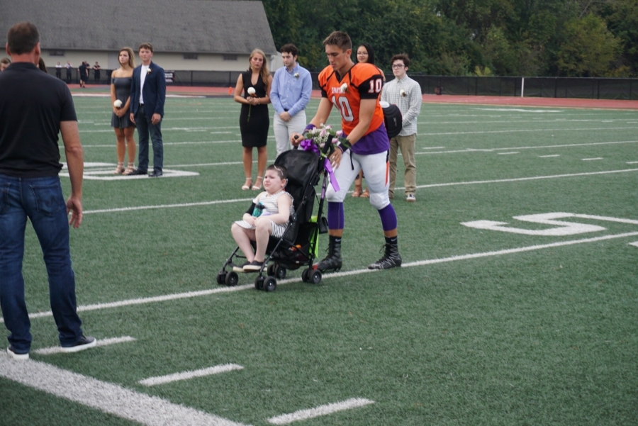 boy in football uniform pushing a stroller